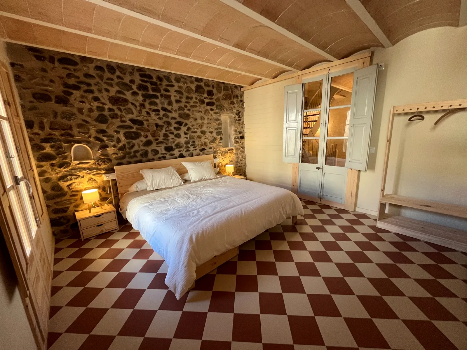 Habitació principal amb paret de pedra i paviment de rajoles a quadres