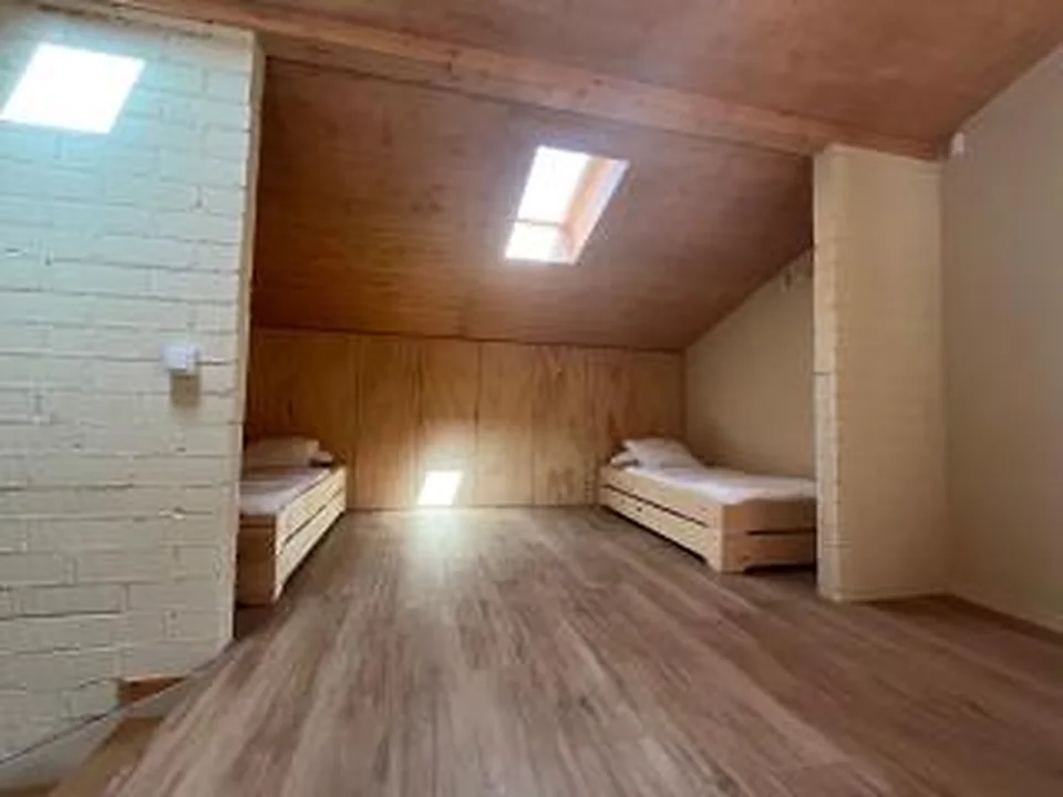 Habitació de fusta amb quatre llits individuals baixos vista des d’un altre angle